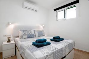 a white bedroom with a bed with blue pillows on it at Casa Joyne in Puerto del Carmen