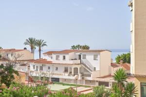 a view of a building with palm trees and the ocean at Apartamento Familiar Torrox A65 in Torrox
