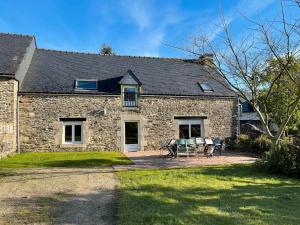 a stone house with two chairs and a table at Les Hortensias - Gîtes in La Croix-Helléan