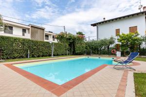 a swimming pool with a chair next to a house at Bluemoon Luminoso apt con piscina in Lazise