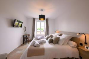 a white bedroom with a large white bed with pillows at Domaine le St Georges - Piscine in Saint-Sauveur-le-Vicomte +27 photos
