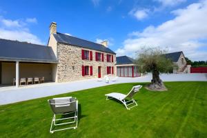 two chairs sitting on a lawn in front of a building at Domaine le St Georges - Piscine in Saint-Sauveur-le-Vicomte