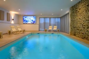 a swimming pool in a hotel room with a tv at Domaine le St Georges - Piscine in Saint-Sauveur-le-Vicomte