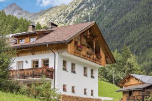 a house with a balcony and mountains in the background at Kuglerhof Apt 1 in Cadipietra