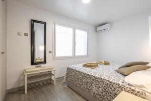 a white bedroom with a bed and a mirror at San Jose in Nerja
