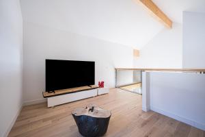 a living room with a flat screen tv and a wooden floor at Black Arves in La Rochette
