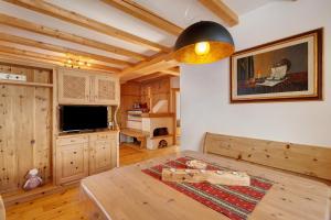 a living room with a table and a television at Lüch dl Pinter in San Martino in Badia