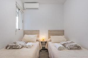two beds in a room with a table and a window at Bright Apartment In Maracena in Granada