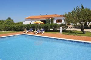 a swimming pool with two chairs and a house at Quinta da Aroeira in Lagoa