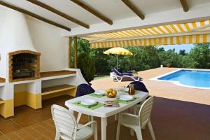 a patio with a table and chairs and a swimming pool at Quinta da Aroeira in Lagoa +11 photos