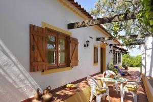 a patio of a house with a table and chairs at Quinta da Aroeira in Lagoa