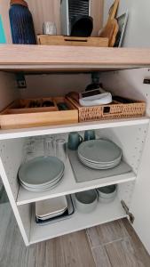 a kitchen shelf with plates and utensils at Casa Neptune in Sausset-les-Pins