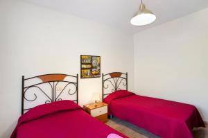 two beds in a room with red sheets at Villa Palomino in Gáldar