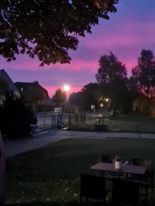a sunset over a park with two picnic tables at Lütt Smedhoff - Appartement Dresden in Gülzow