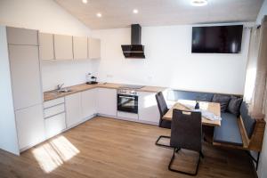 a kitchen with white cabinets and a wooden table at Kleines Glück Wettenberg in Hochdorf