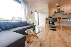 a living room with a blue couch and a glass table at Ferienwohnung Talblick in Kappelrodeck