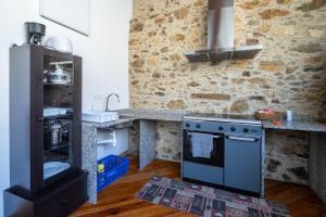 a kitchen with a stove and a stone wall at Casa Silverio in Monforte de Lemos