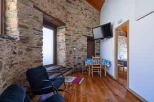 a living room with a stone wall and a tv at Casa Silverio in Monforte de Lemos