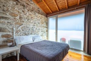 a bedroom with a bed and a stone wall at Casa Silverio in Monforte de Lemos +16 photos