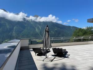 a patio with two chairs and an umbrella on a roof at Alpenblick De Luxe in Oetz