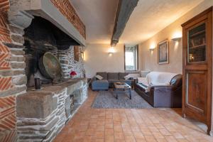 a living room with a couch and a stone fireplace at Les Hortensias - Gîtes in La Croix-Helléan