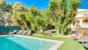 a backyard with a swimming pool and palm trees at Costacabana - Villa Summertime in Lloret de Mar