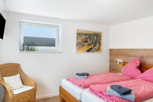 a bedroom with a bed and a chair and a window at Landhaus Gerda in Wangerland