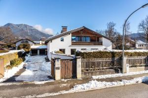 a white house with a fence in the snow at Alpview Loft Garmisch in Garmisch-Partenkirchen