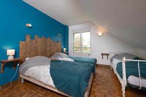 a bedroom with two beds and a blue wall at Les Hortensias - Gîtes in La Croix-Helléan