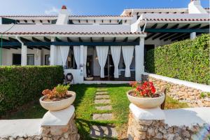 a house with two stone vases with flowers in it at Maison Menorca in Arenal d'en Castell