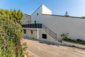 a white building with a staircase next to a road at Canto Cigalo Duplex 12 in Robion en Luberon