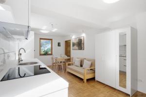 a white kitchen and living room with a couch and a sink at Mini Trenta in Soča