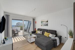 a living room with a gray couch and a balcony at Casa Agua Y Sol I in Poris de Abona
