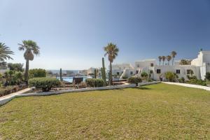 a lawn in front of a resort with palm trees at Casa Agua Y Sol I in Poris de Abona