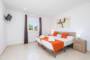 two beds in a bedroom with white walls and orange pillows at Ca Na Bergues in Ariany +21 photos