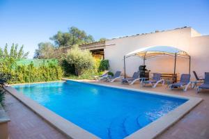 a swimming pool with chairs and an umbrella next to a house at Ca Na Bergues in Ariany