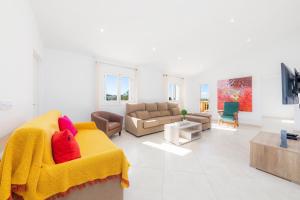 a living room with a yellow couch with red pillows at Ca Na Bergues in Ariany