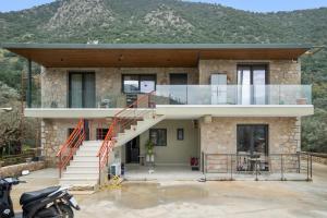 a house with a glass facade with mountains in the background at Sokol stone house in Vlikhón
