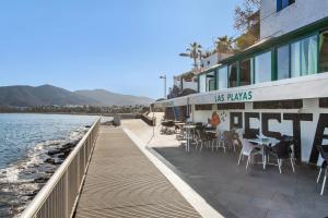 a restaurant with tables and chairs next to the water at Neral relax in Las Playitas