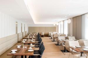 a restaurant with wooden tables and white chairs at NH Collection Wien Zentrum in Vienna