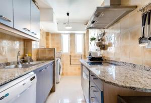 a kitchen with white cabinets and marble counter tops at Denia Living in Denia