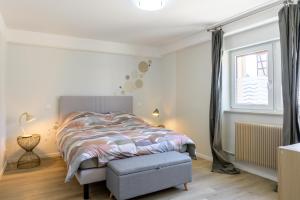 a white bedroom with a bed and a window at Au Bretzel in Ostheim