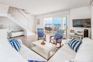 a living room with a white couch and blue chairs at Casa Miramar in Sa Ràpita