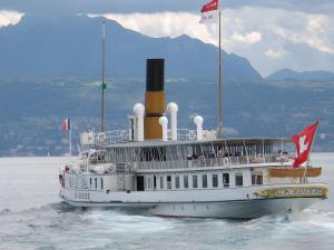 a ferry boat on the water with a mountain in the background at Gîte Chez Fanfoué in Orcier