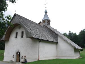 a small white church with a steeple with two children in front at Gîte Chez Fanfoué in Orcier