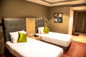 two beds in a hotel room with green pillows at Banyan Palace in Chennai