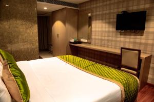 a hotel room with a bed and a flat screen tv at Banyan Palace in Chennai