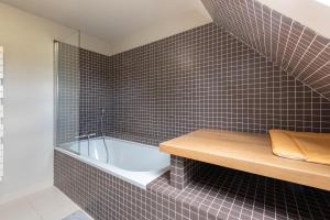a bathroom with a tub and a tile wall at Villa Delb in Arthez-dʼAsson +22 photos