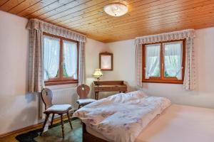 a bedroom with a bed and a desk and windows at Stecher's Hüsli in Titisee-Neustadt