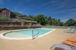 a swimming pool with two chairs and a fence at Maisons Cozy - Mas Lachamp in Gravières